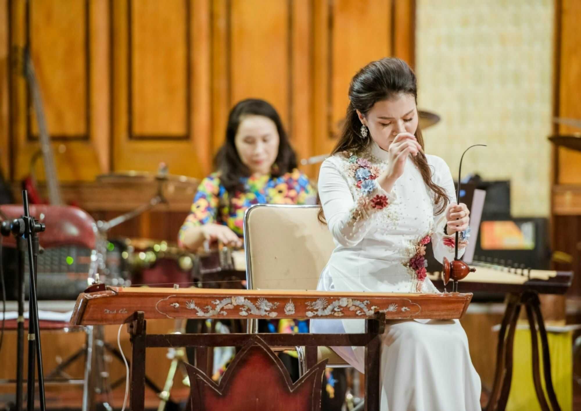 Close-up photograph of a skilled musician playing the dan bau with traditional technique